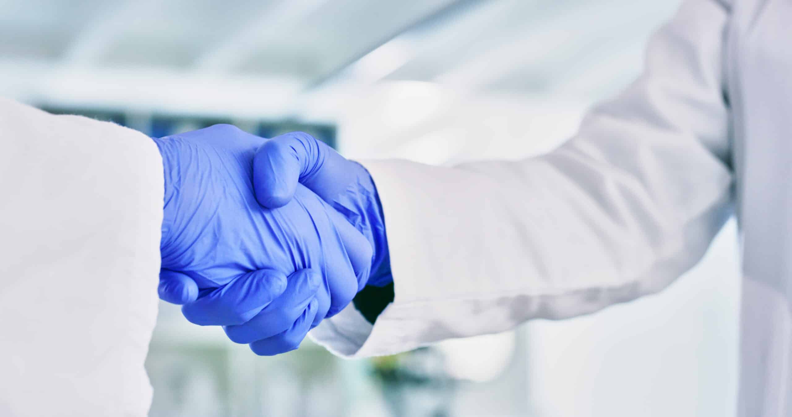 Closeup shot of two unrecognisable scientists shaking hands in a lab
