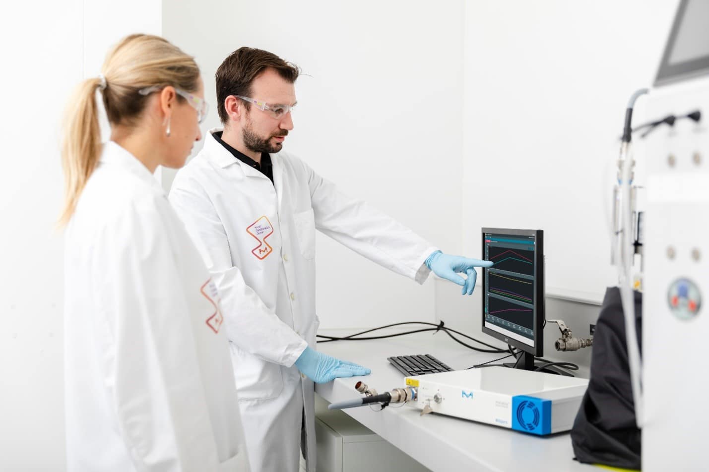 Two operators in a lab operating a Raman system and analyzing the data from their bioprocess activities.